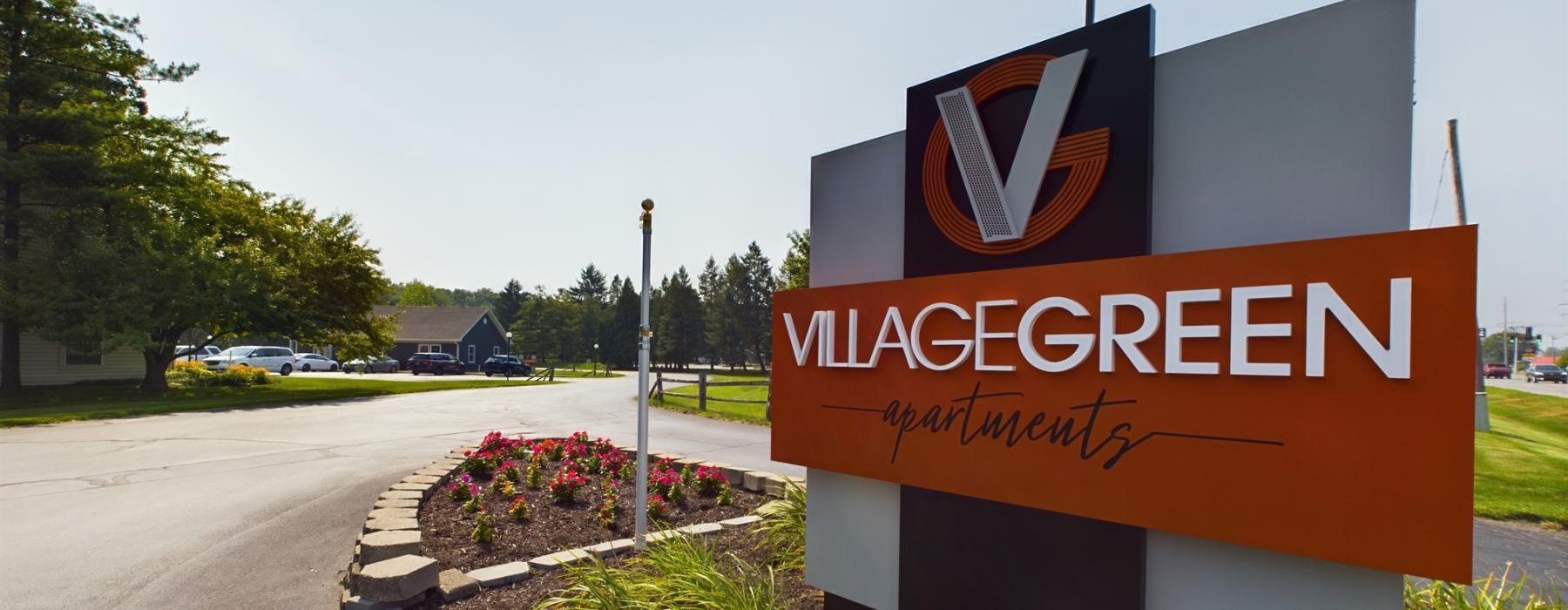 a sign at the entrance of Village Green Apartments